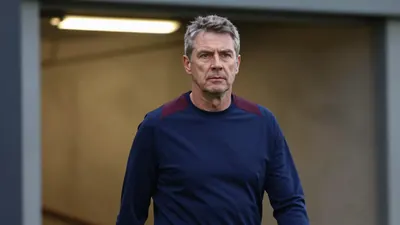 A 50-year-old male ST Johnstone manager, dressed in a plain navy blue and dark claret polyester training top, stands in...
