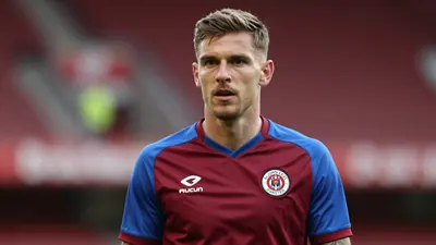 A determined St Johnstone midfielder, 25, with a strong build, wears a claret shirt with blue sleeves, made of smooth...